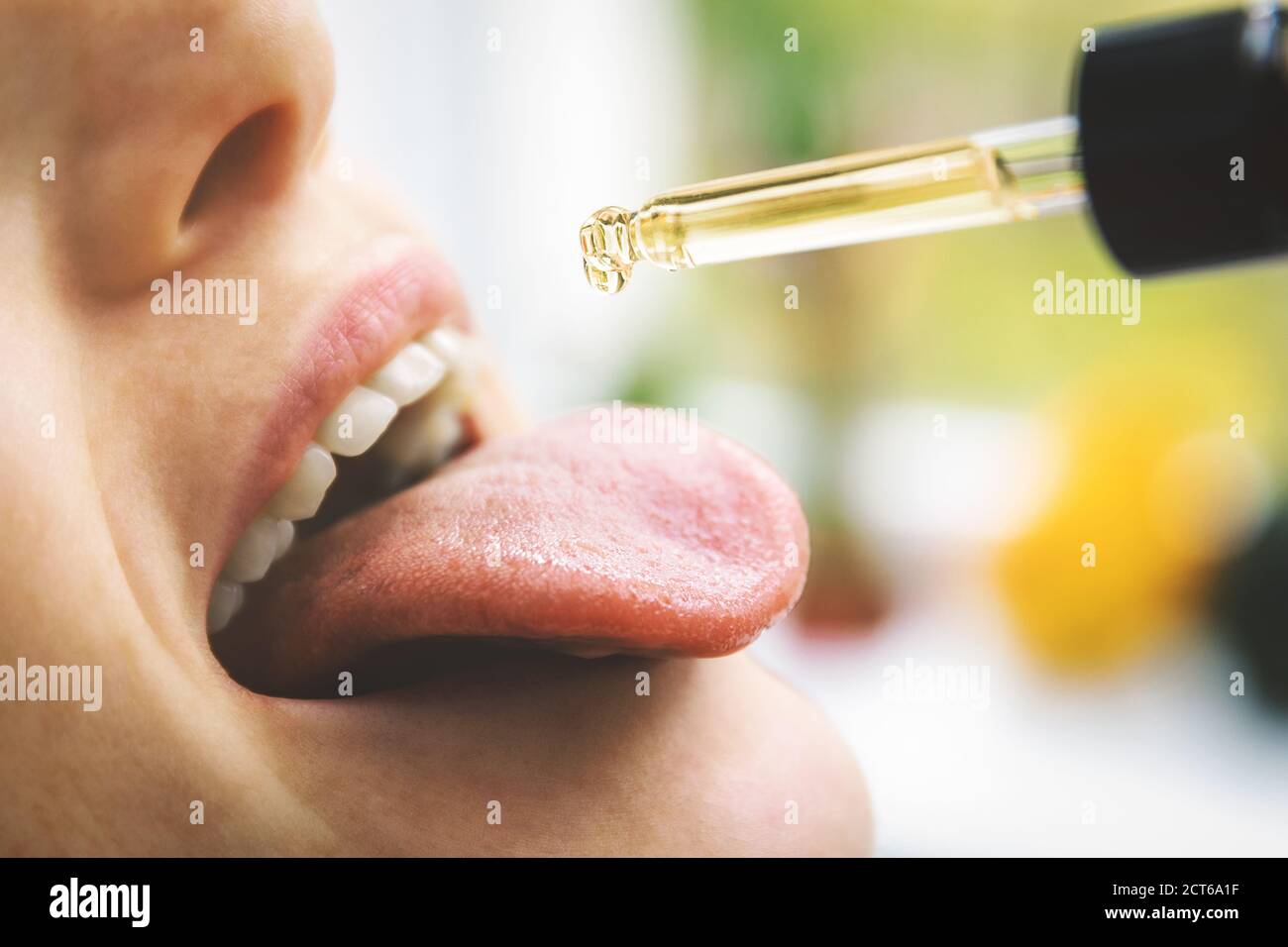 herbal alternative medicine and dietary supplements - woman taking cbd hemp oil drops in mouth from dropper. medical cannabis Stock Photo
