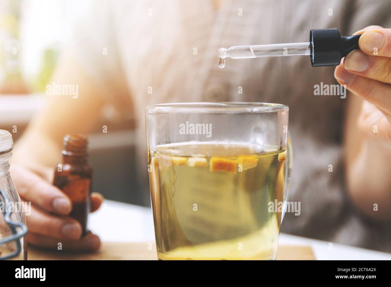 dietary supplements and vitamins - woman adding drops in cup of tea with dropper. Stock Photo