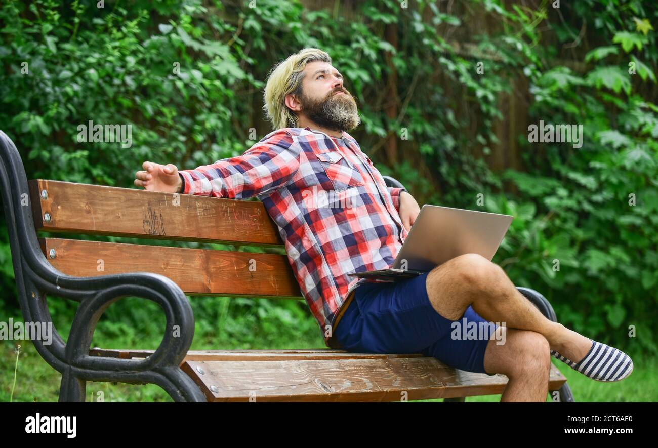 Hipster inspired work in park. Modern laptop. Remote job. Fresh air. Mobile internet. Online shopping. Agile business. Bearded guy sit bench park nature background. Work and relax. Working online. Stock Photo