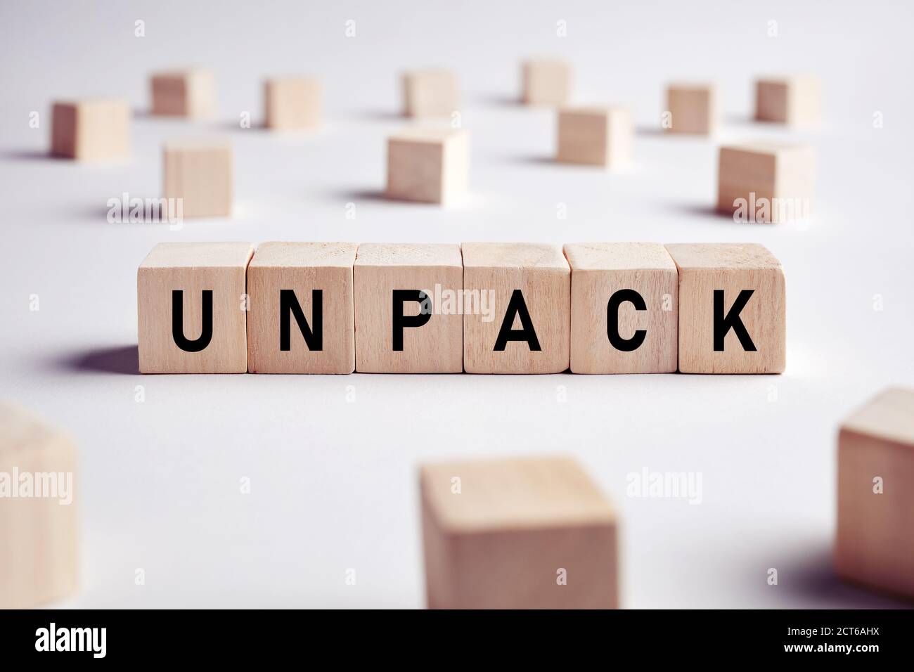 The word unpack on wooden cubes on white background. House removal and unpacking concept. Stock Photo