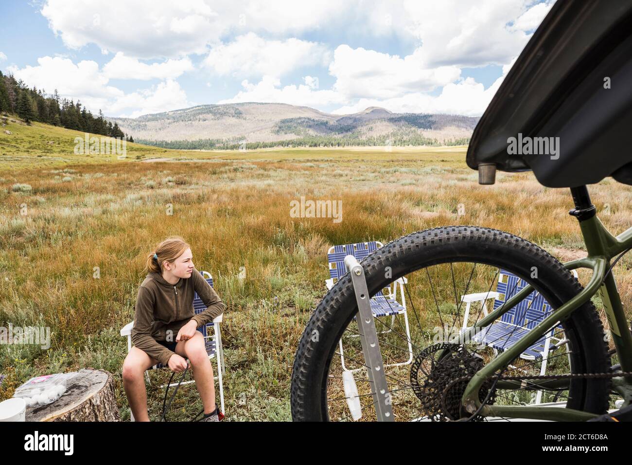 A Teenage girl sitting in an open landscape preparing for a bike ride. Stock Photo