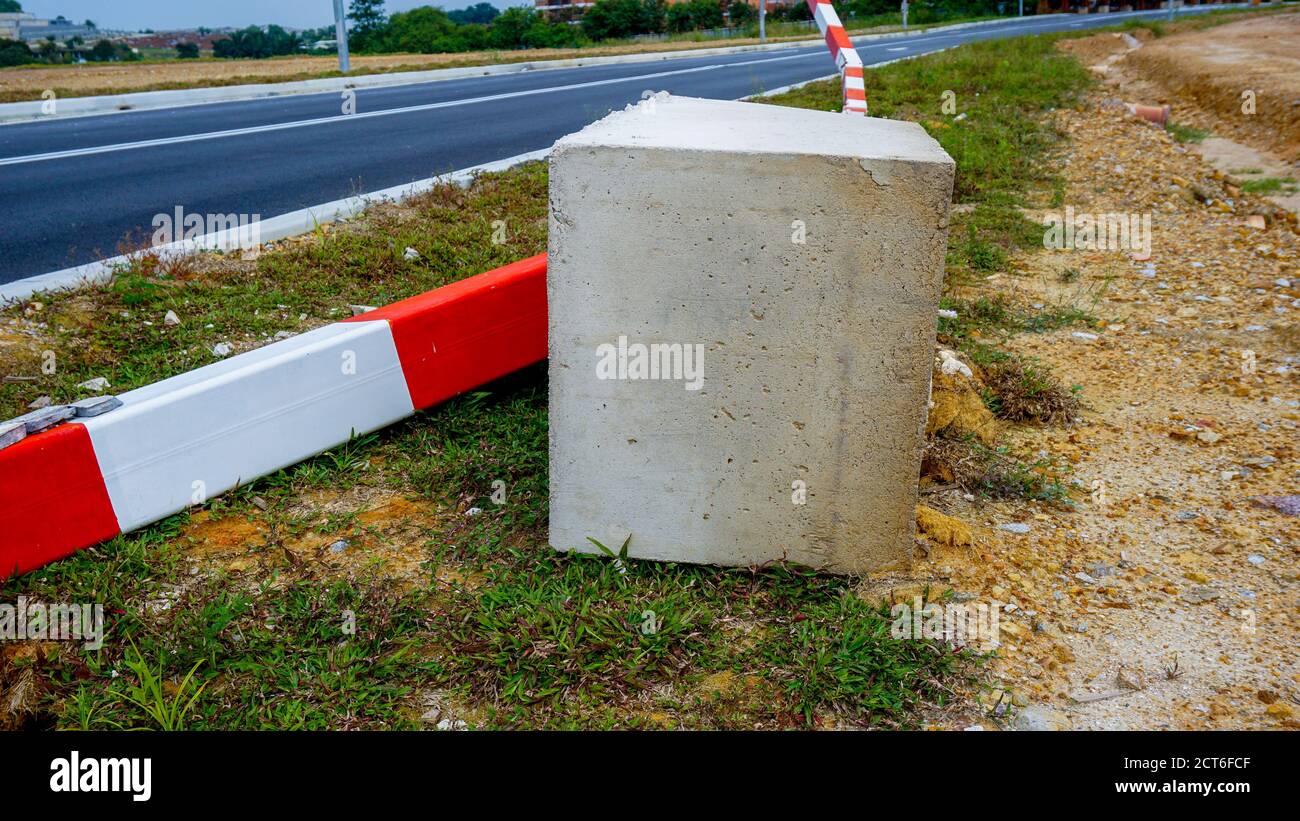 Red and white striped concrete road barrier lying on the road side ...