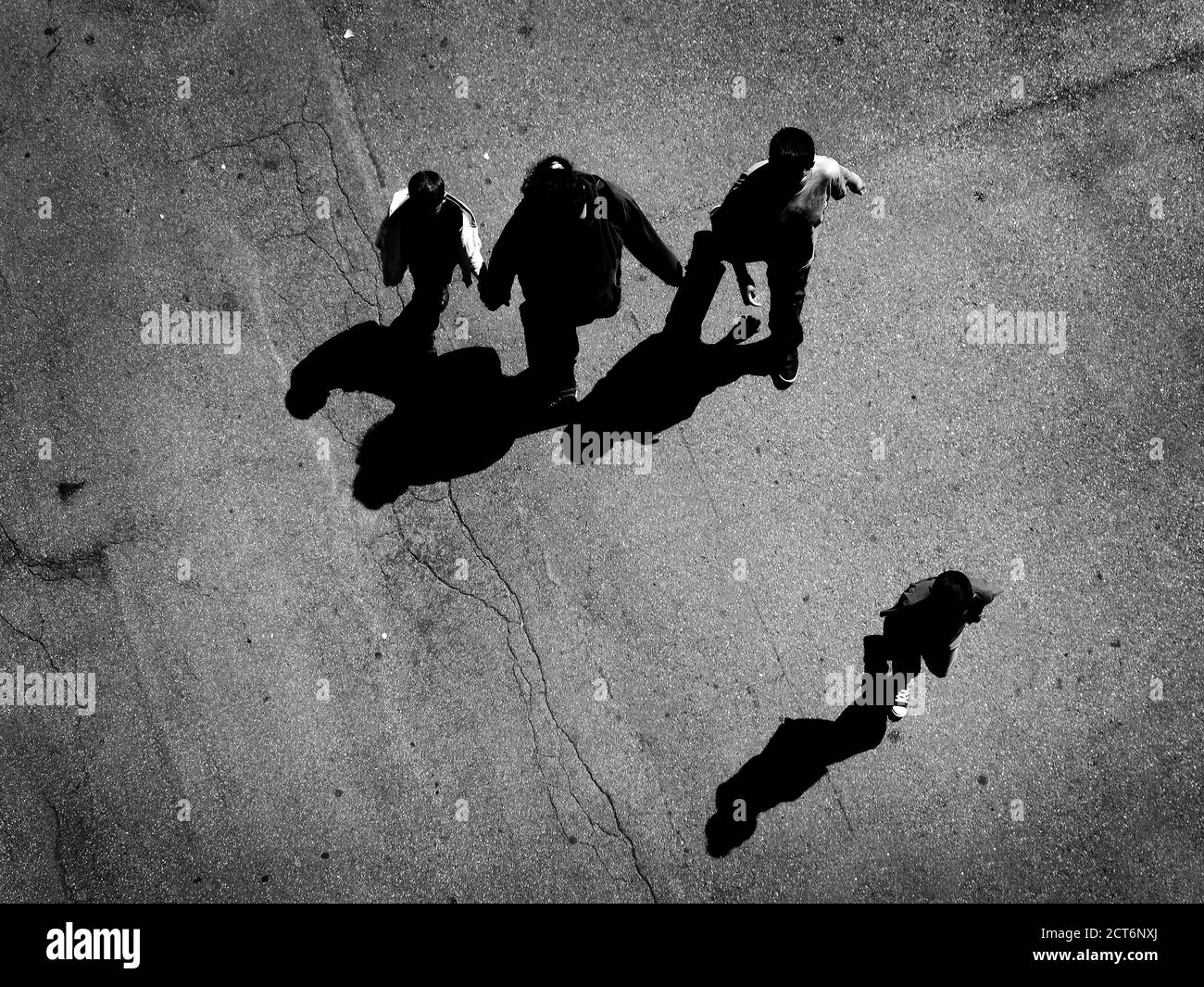 Several people walking down below on concrete with shadows aerial view from above Stock Photo