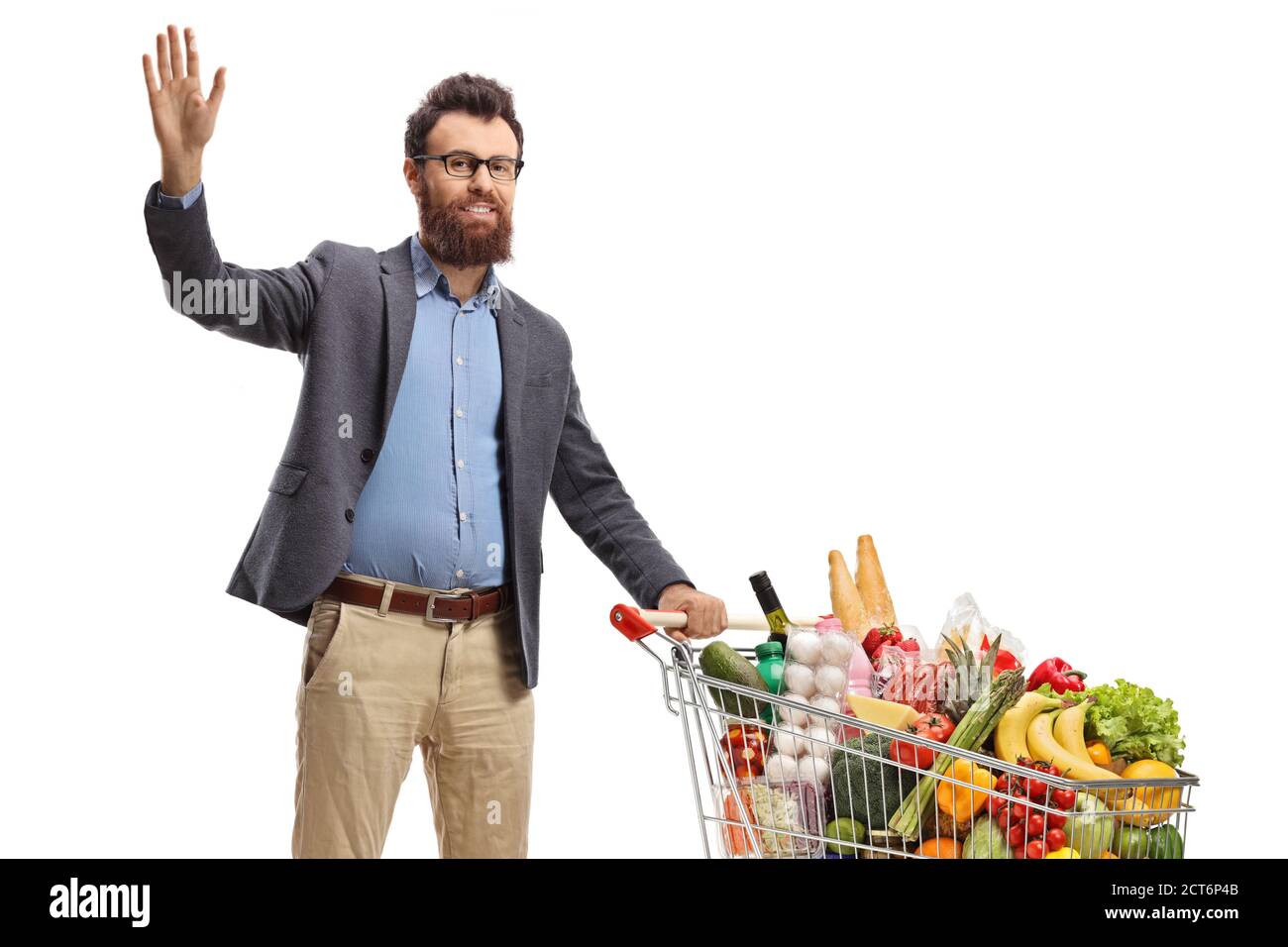Bearded man standing with a shopping cart and waving isolated on white background Stock Photo