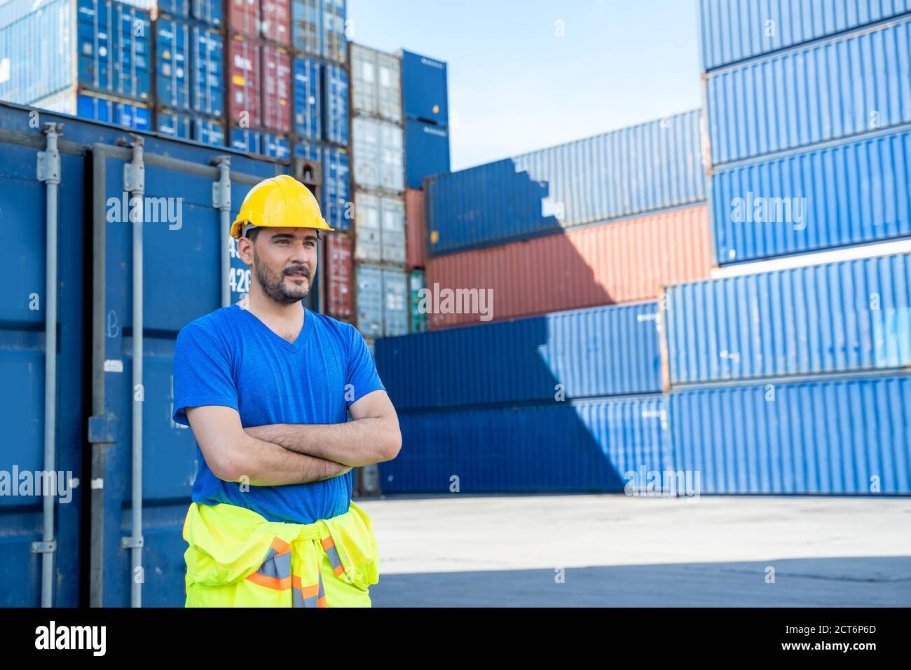 Portrait of container worker leaning on cargo container and looking up ...