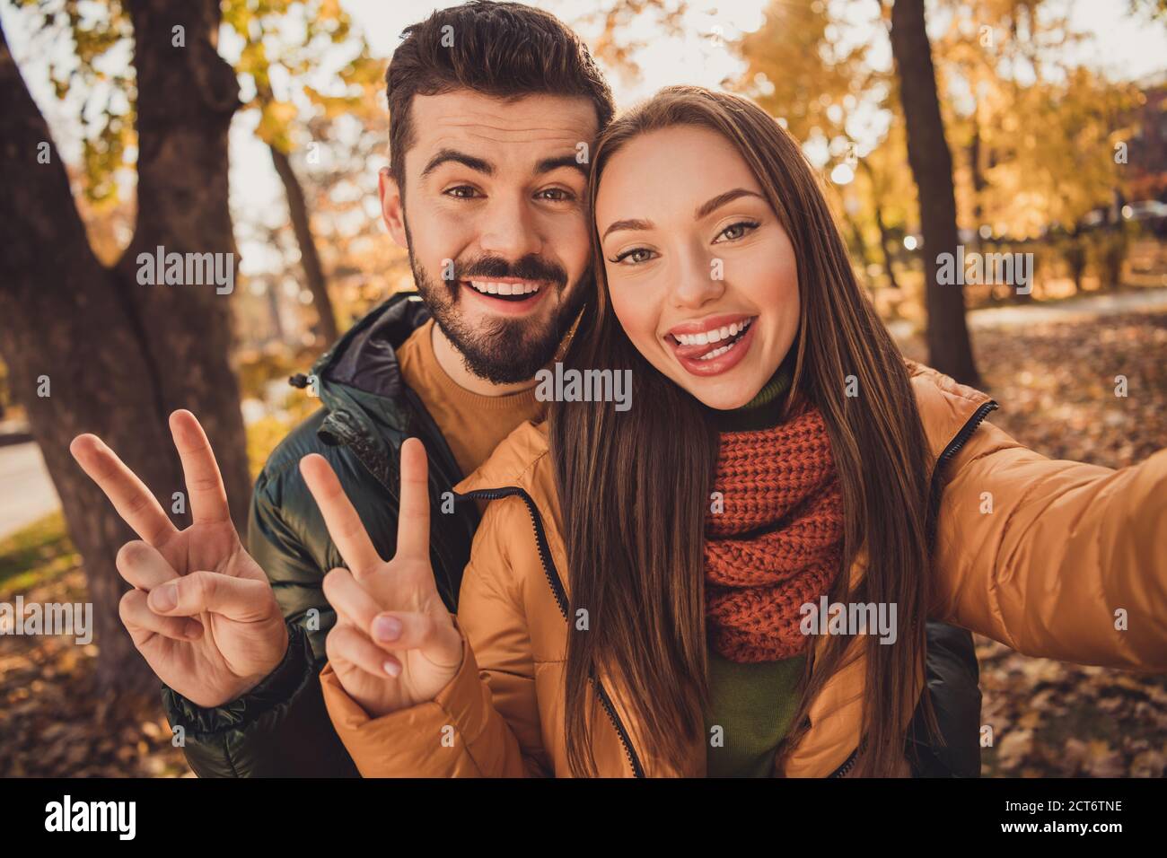 portrait of positive two people students couple take selfie make v sign symbol show tongue out in autumn park 2CT6TNE