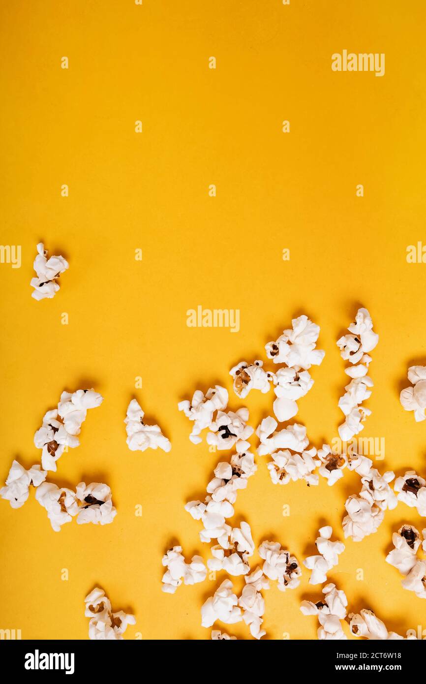 Popcorn scattered on yellow background Stock Photo