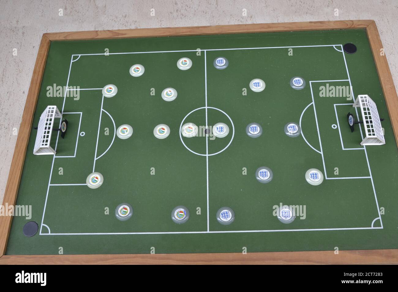 Button football, toy with English and Italian football team players, top view, with wooden field on green background. Stock Photo