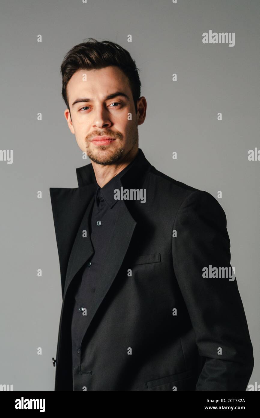 Portrait of a young handsome man in a black suit, standing and ...