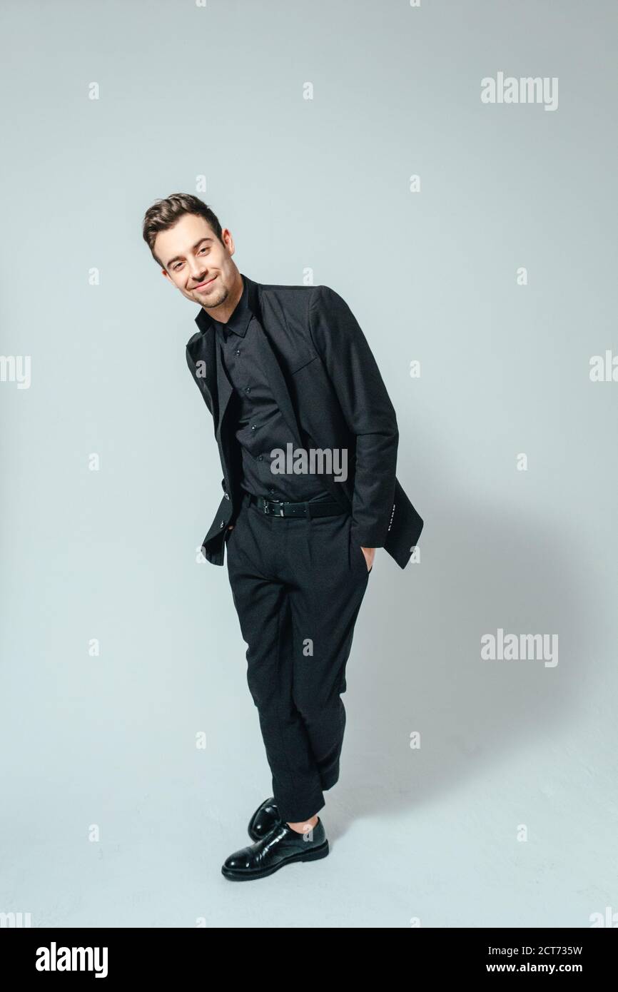 Portrait of a young handsome man in a black suit, smiling and looking ...