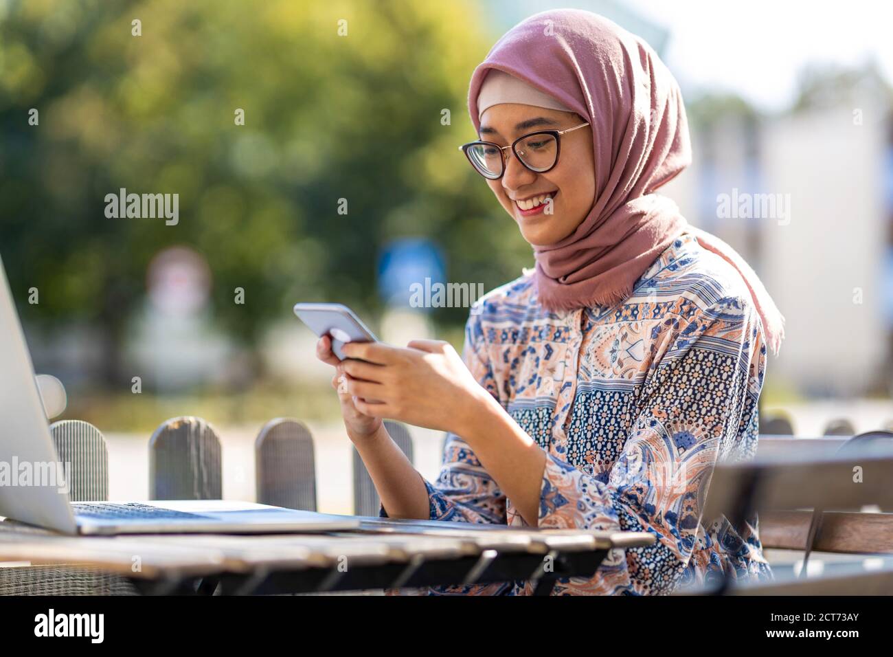 Young Muslim woman using a laptop in outdoor cafe Stock Photo - Alamy