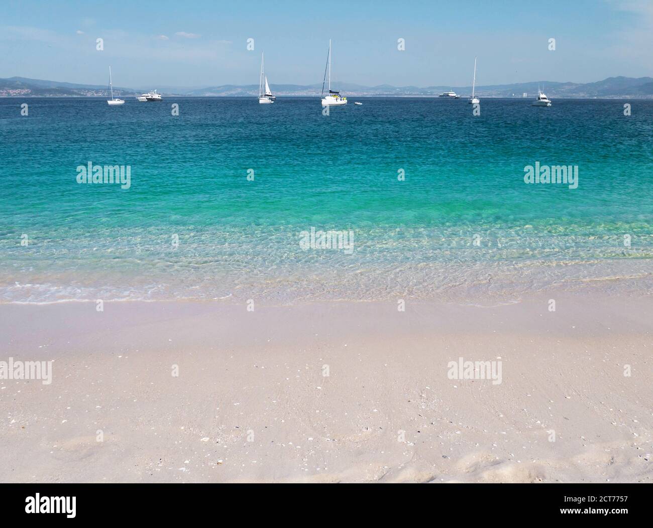 Turquoise sea and white sandy Rodas beach at the Cies islands, Galicia, Spain. Crystal clear shallow water and boats. Stock Photo