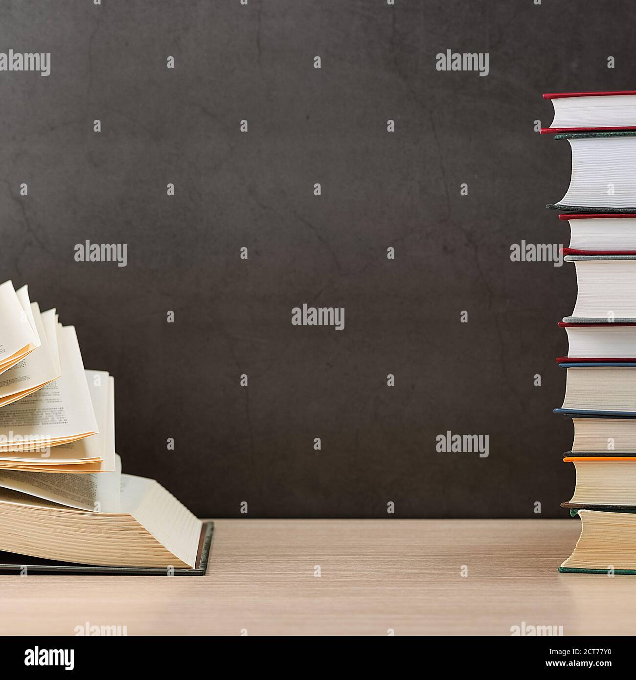 A large, thick hardcover book is lying on a light wood table. The book ...