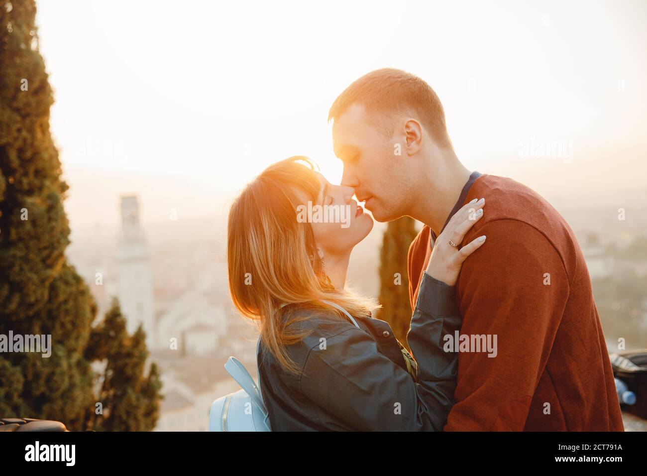 Romantic couple man and girl hug and kiss on sunset background of city Verona Italy. Travel concept Stock Photo