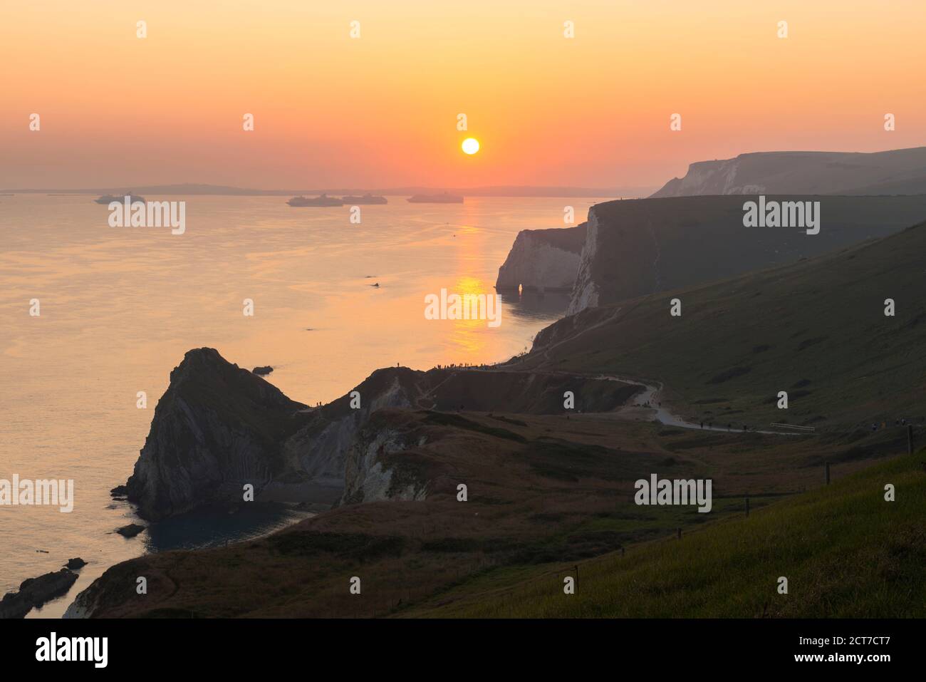 West Lulworth, Dorset, UK.  21st September 2020.  UK Weather. The sky glows orange above the Jurassic Coast at sunset viewed from the South West Coast Path above Durdle Door near West Lulworth in Dorset at the end of a hot autumn day.  Picture Credit: Graham Hunt/Alamy Live News Stock Photo
