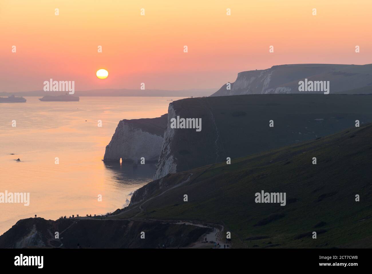 West Lulworth, Dorset, UK.  21st September 2020.  UK Weather. The sky glows orange above the Jurassic Coast at sunset viewed from the South West Coast Path above Durdle Door near West Lulworth in Dorset at the end of a hot autumn day.  Picture Credit: Graham Hunt/Alamy Live News Stock Photo