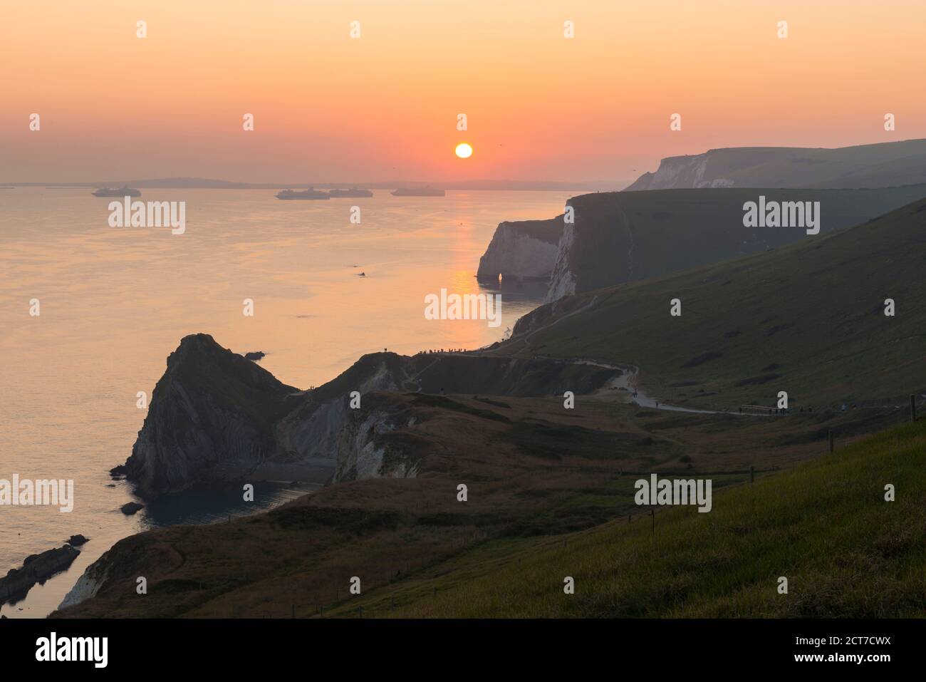 West Lulworth, Dorset, UK.  21st September 2020.  UK Weather. The sky glows orange above the Jurassic Coast at sunset viewed from the South West Coast Path above Durdle Door near West Lulworth in Dorset at the end of a hot autumn day.  Picture Credit: Graham Hunt/Alamy Live News Stock Photo
