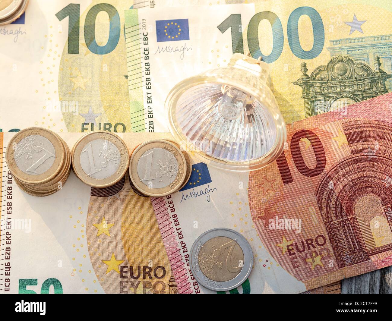 LED light bulb on euro coins and euro bills. Concept for electricity