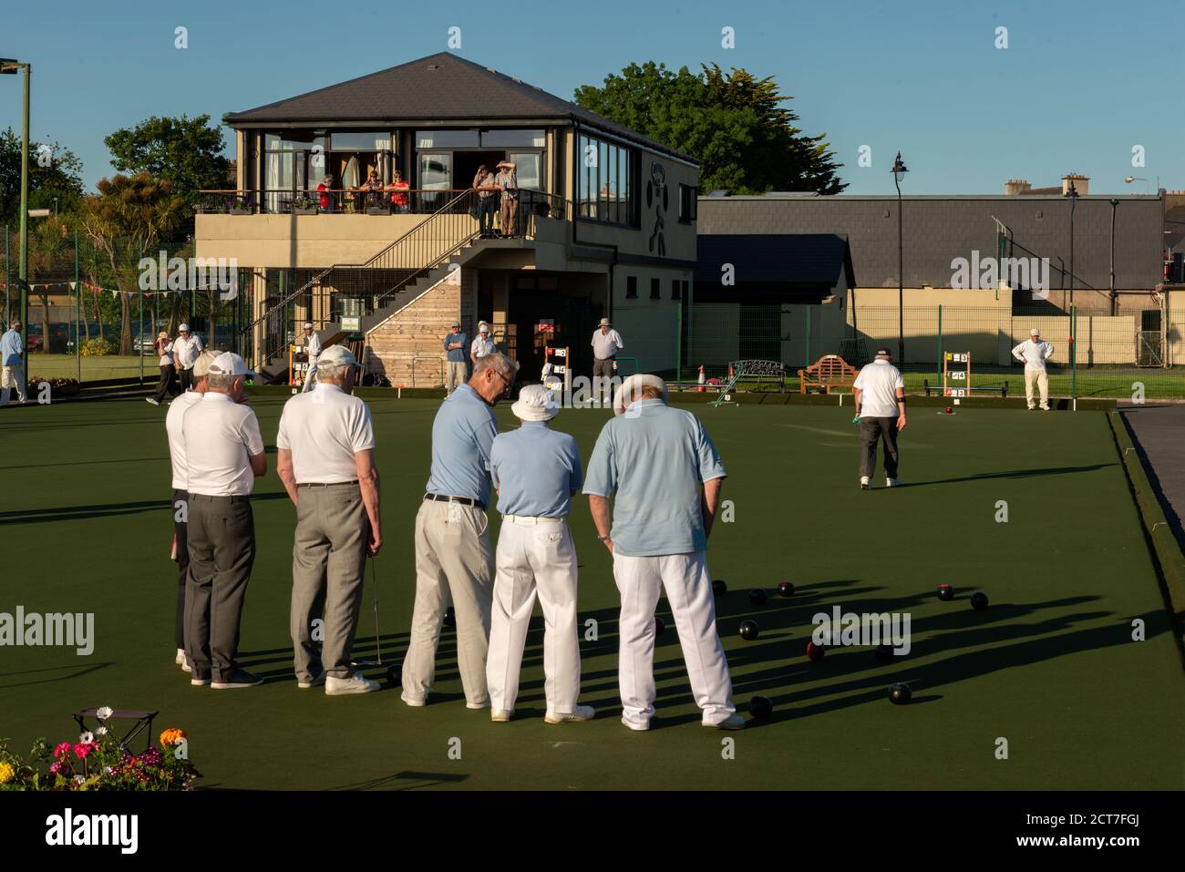 Several senior men playing lawn bowls at The Causeway Tennis and Bowls Club in late afternoon with low sunset light Dungarvan Ireland Stock Photo