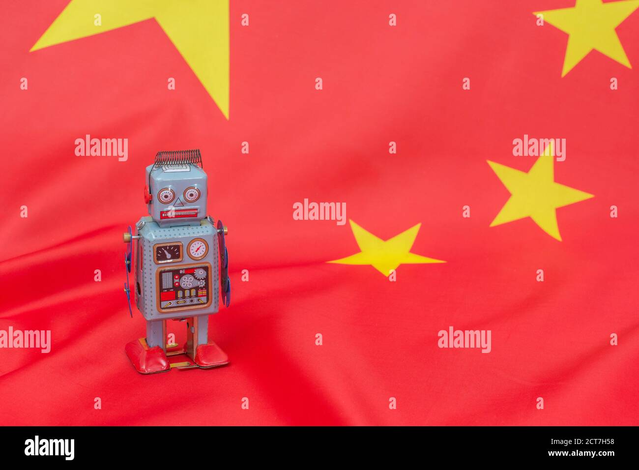 Wind-up clockwork toy robot on Chinese flag. For Chinese bots influencing US elections, advances in Chinese AI, China troll farm, China AI. Copy space Stock Photo