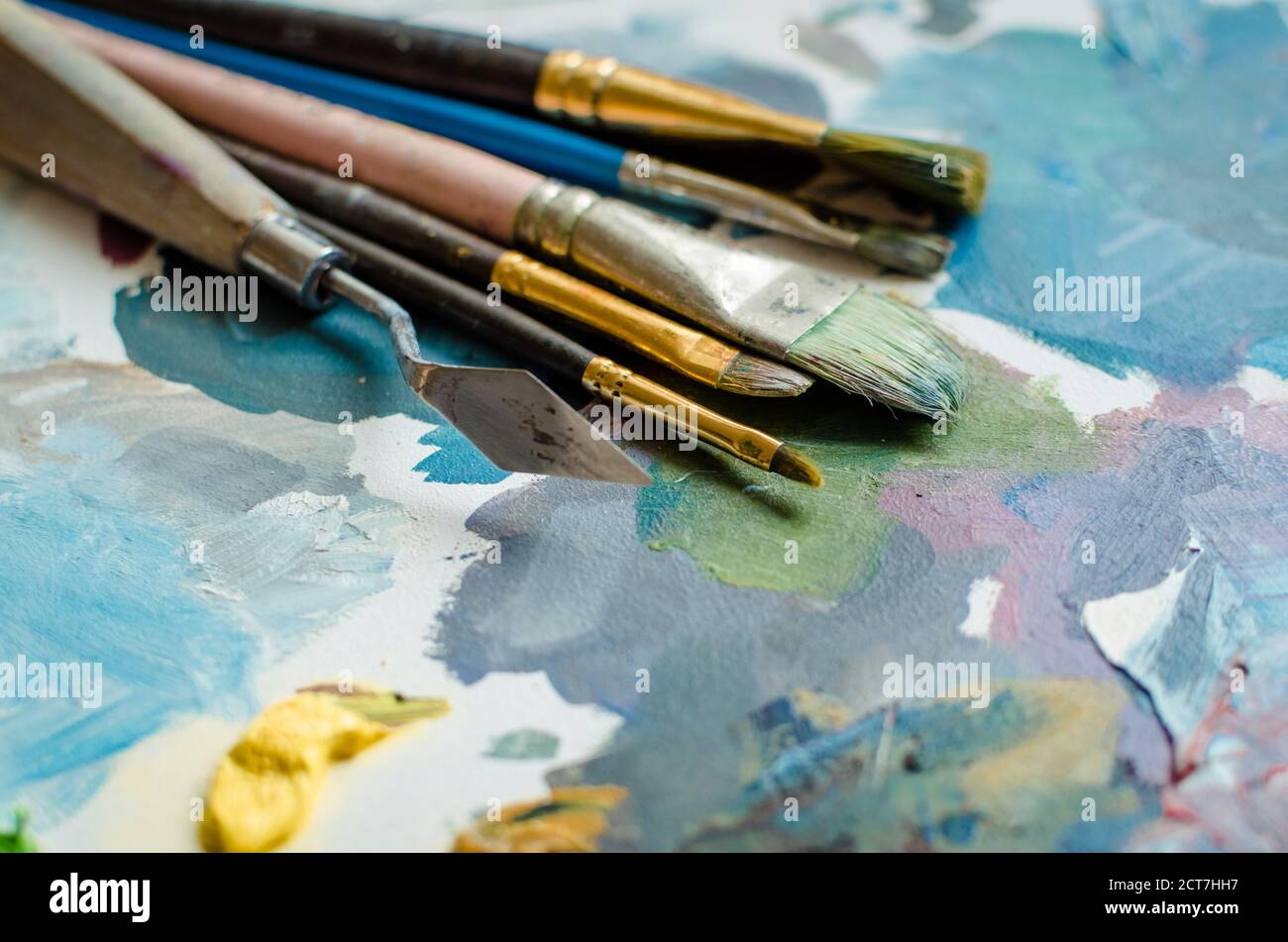 Artist paint brushes on wooden palette. Texture mixed oil paints in ...