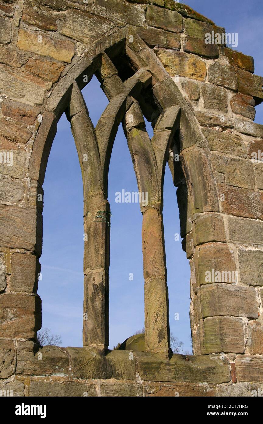 Ruined church window surrounded by stonework with a blue sky behind . Stock Photo