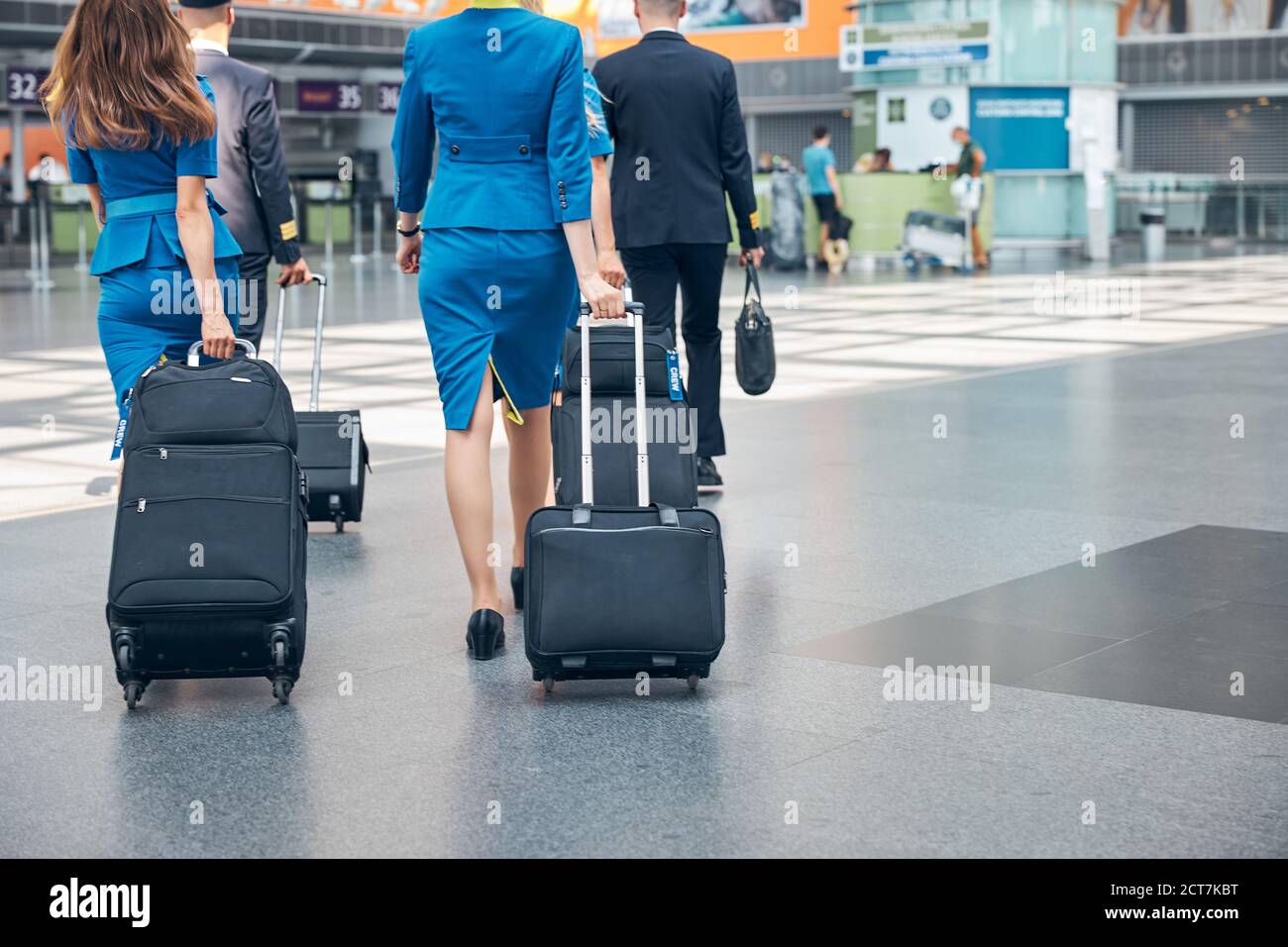 Aircrew members carrying travel suitcases in airport terminal Stock Photo