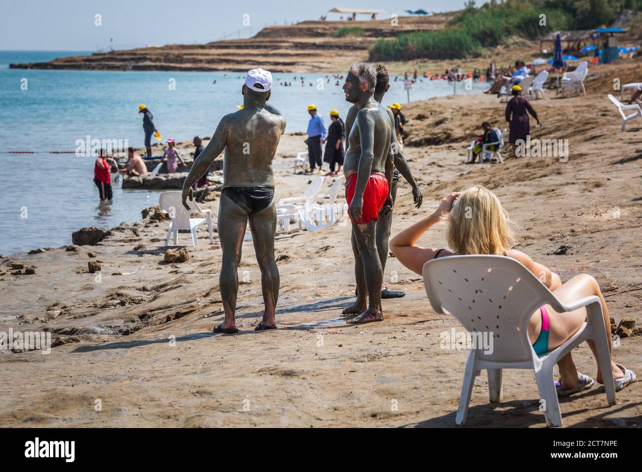 Tourists applying Dead Sea mud which possesses the medicinal qualities and helps to the people with skin problems. Body care treatment in Israel. Dead Stock Photo