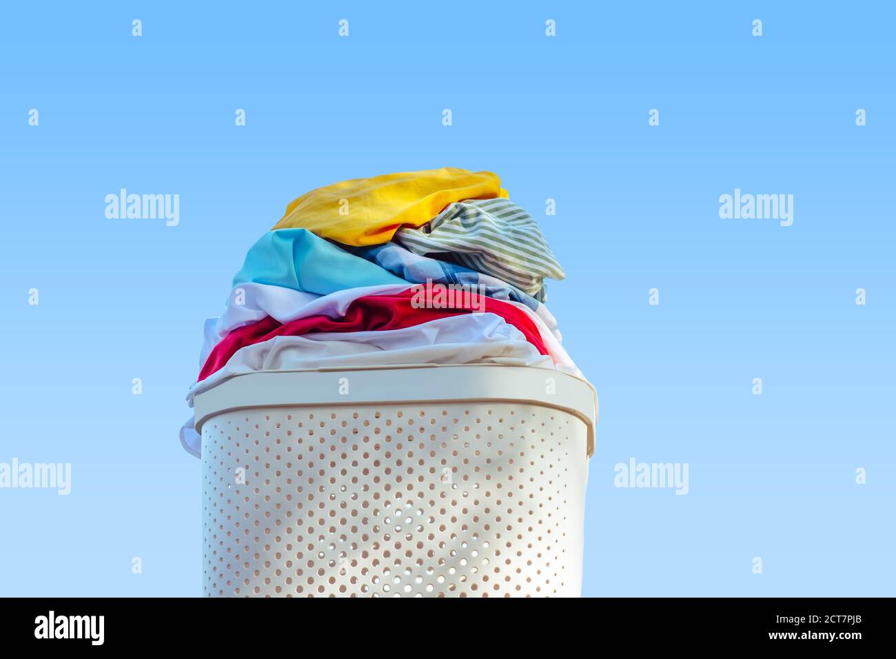 Laundry basket full of clothes.On a blue background Stock Photo