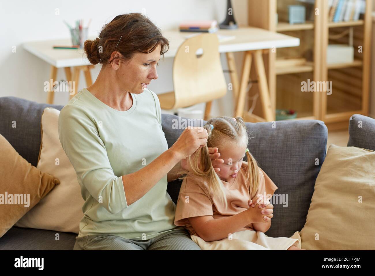 Side view portrait of loving mother combing hair of cute girl with down