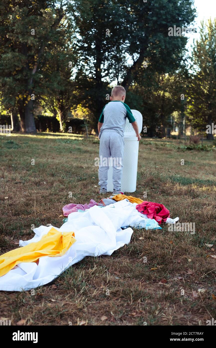 the kid throwing clothes out of the basket. outdoor Stock Photo Alamy