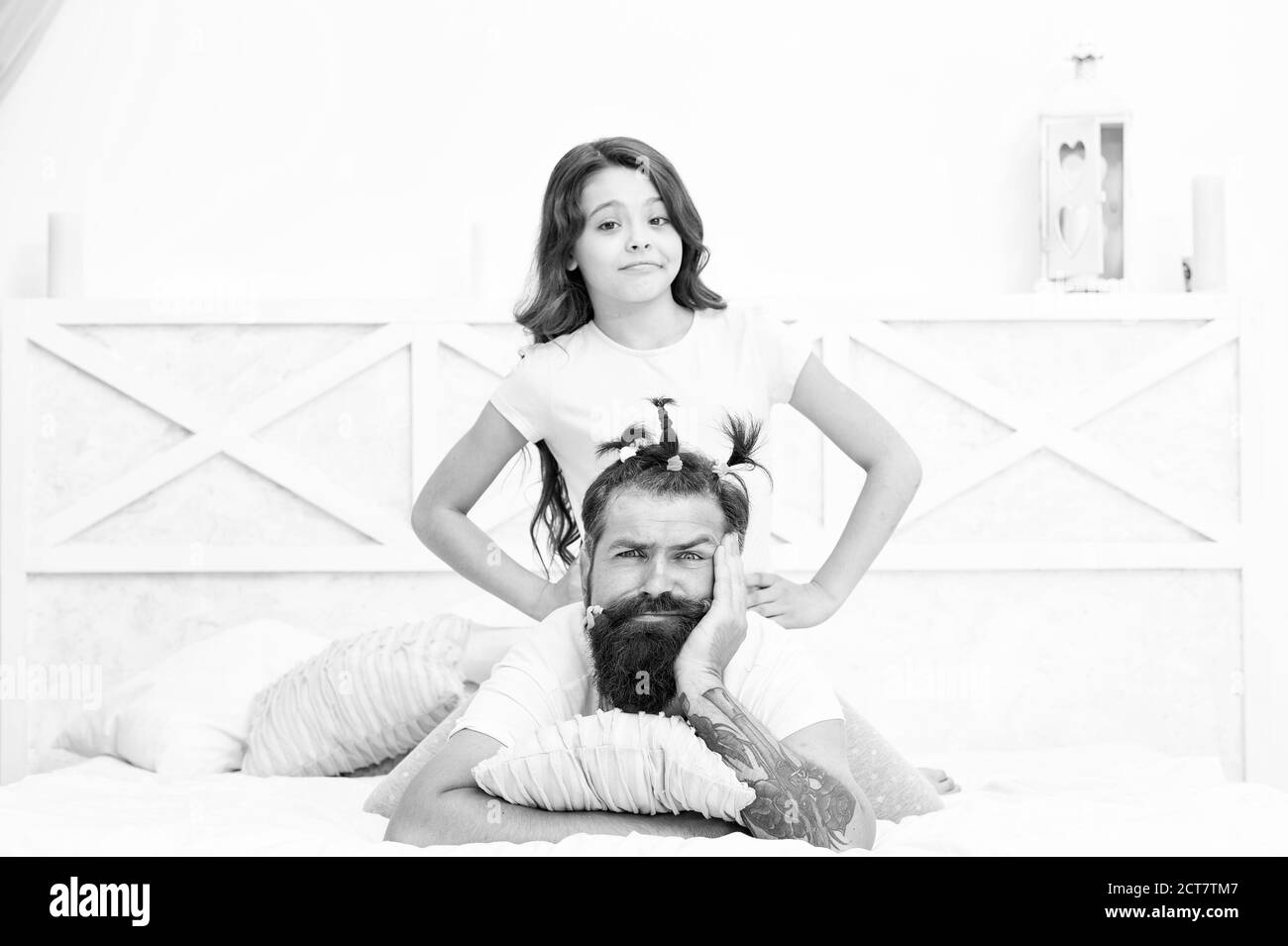 Pajamas party. Hairdresser or stylist. Funny hairstyle. Compressed into boundaries of home. Happy childhood. Relaxing in bedroom. Girl and dad. Quarantine with children. Happy family. Family leisure. Stock Photo