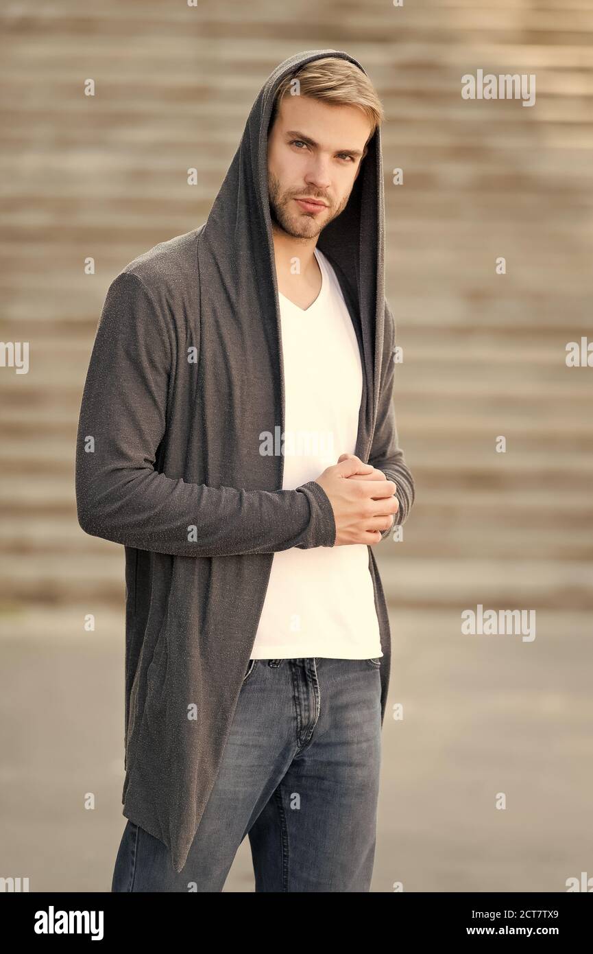 Male fashion influencer. Fashionable young model man. Carefree guy street  style outfit with hood. Handsome man with hood standing urban background.  Fashion trend. Comfortable clothes for daily wear Stock Photo