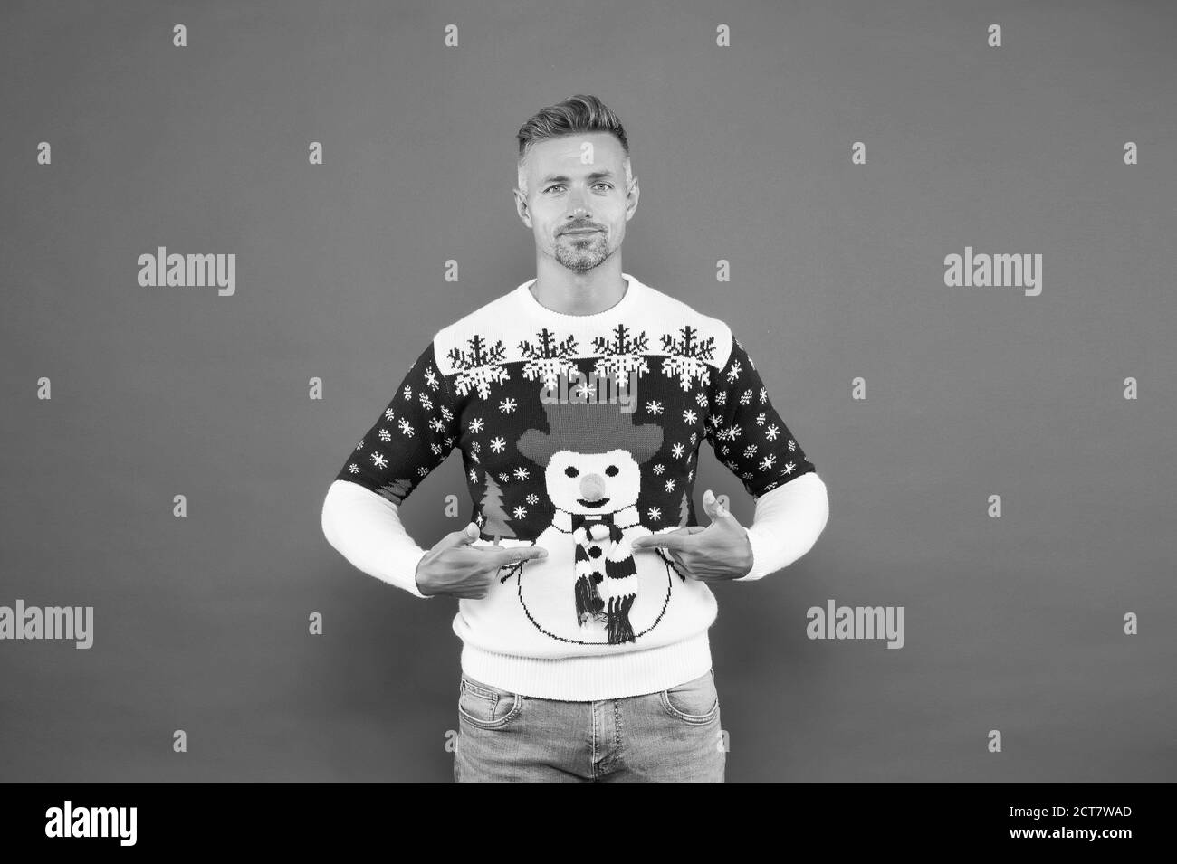 Product for sale. Handsome man point fingers at snowman christmas jumper. What to wear for christmas party. Christmas outfit for stylish celebration. Merry christmas. Happy new year. Stock Photo