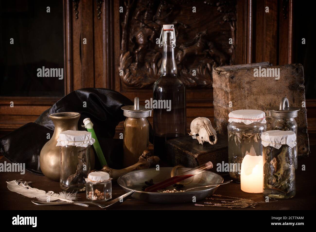 eerie witches' kitchen with lot of ingredients for a potion and ancient gruesome jars dark with only candlelight for Halloween Stock Photo