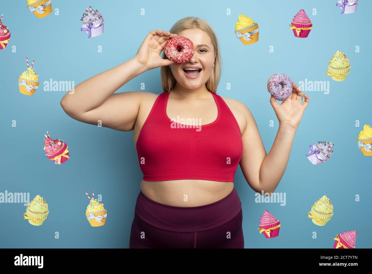 Fat woman eats sweet instead of do gym. Cyan background Stock Photo