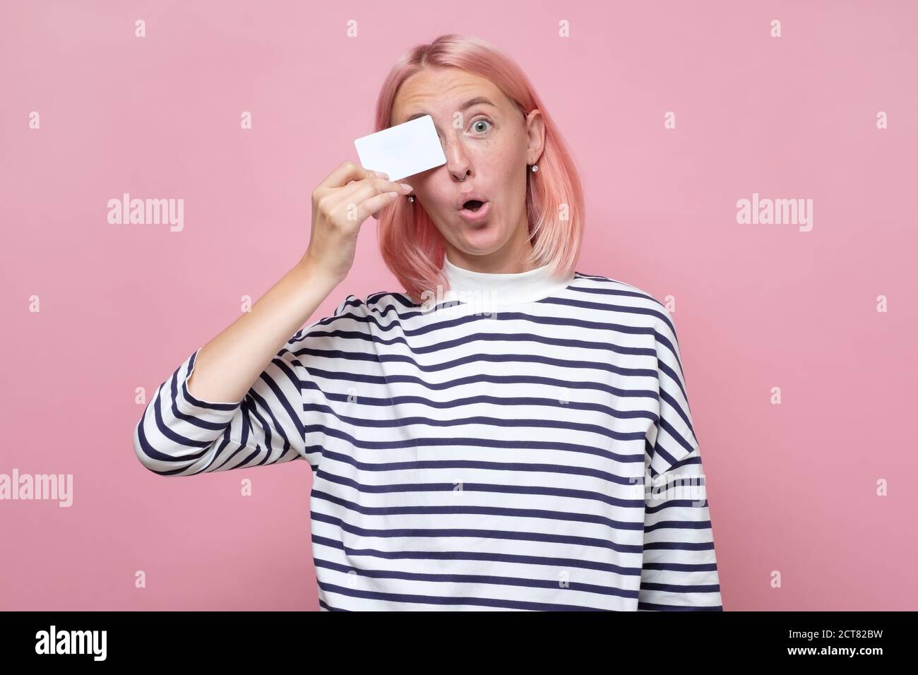 Smiling woman in striped clothes holding her empty visiting card Stock Photo