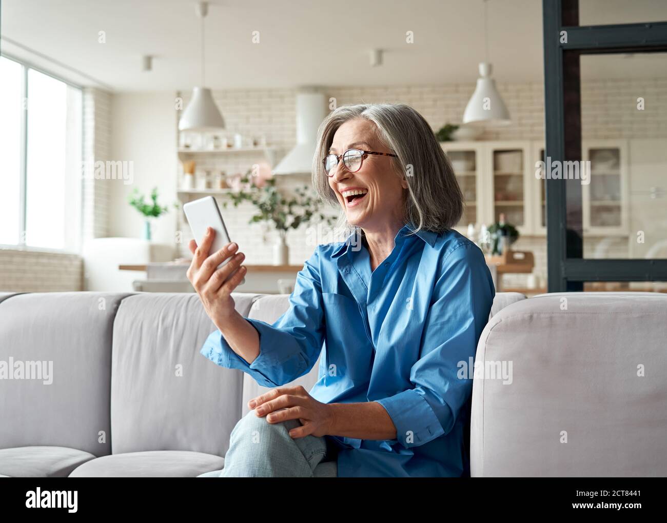 Happy mature old woman holding smartphone using mobile phone app for video call. Stock Photo