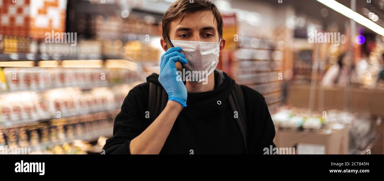 close up. young man in a protective mask talking on his smartphone ...