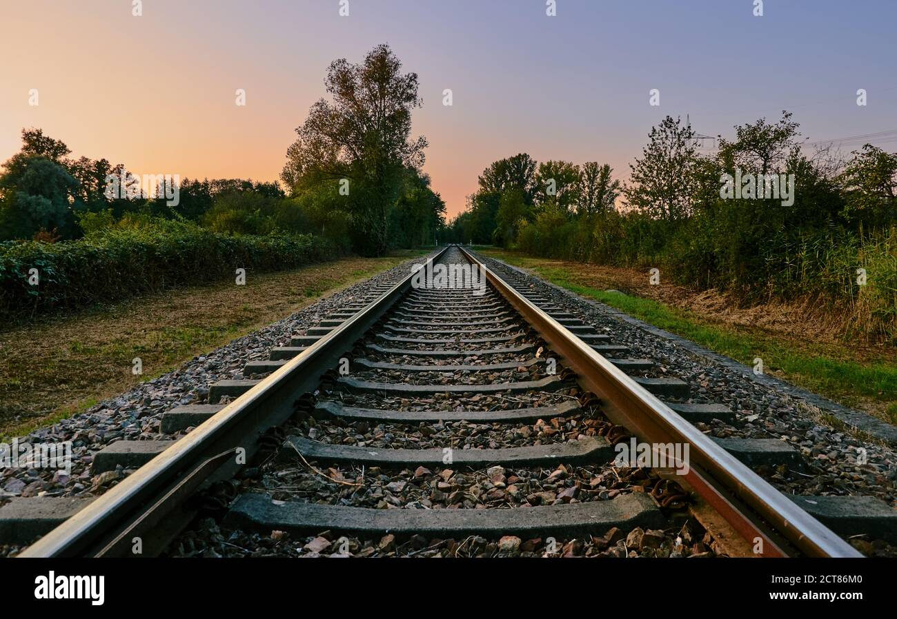 Rail track in landscape with colorful sky and sunset on a beautiful summer evening Stock Photo
