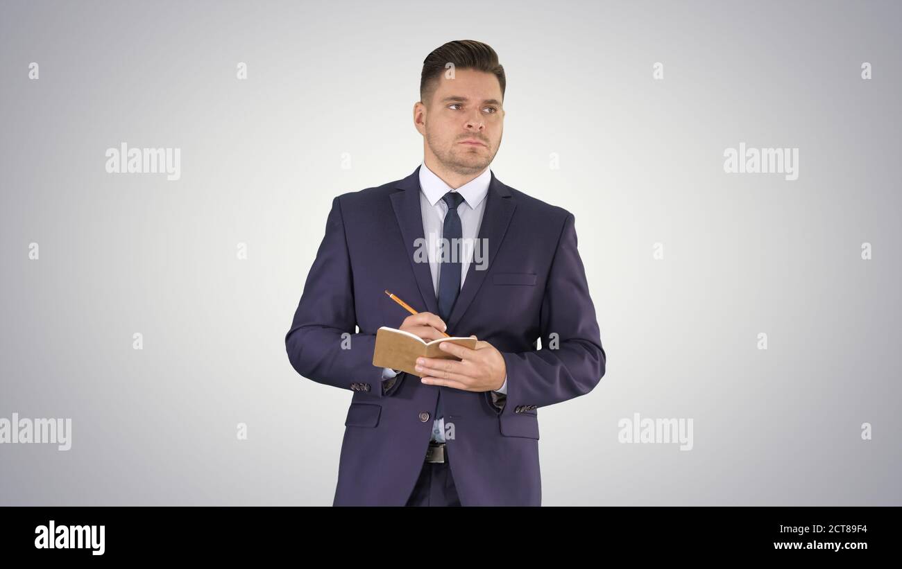 Handsome experienced manager writing in notebook his ideas while Stock Photo
