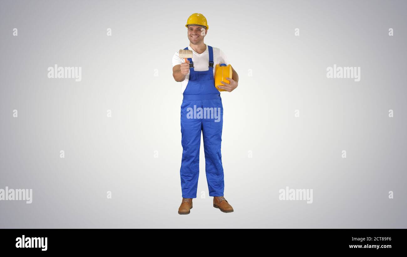 Worker holding paint brush smiling to camera on gradient backgro Stock Photo