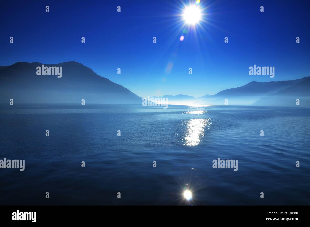 Foggy Alpine lake Maggiore with Sunbeam and Mountain in Ticino, Switzerland. Stock Photo