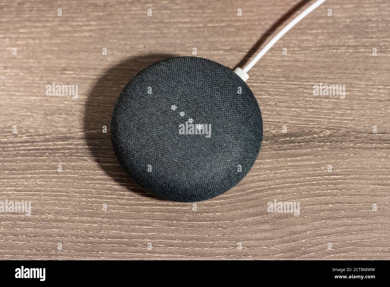 Gray Google Home Mini Smart Speaker on Office Desk Stock Photo
