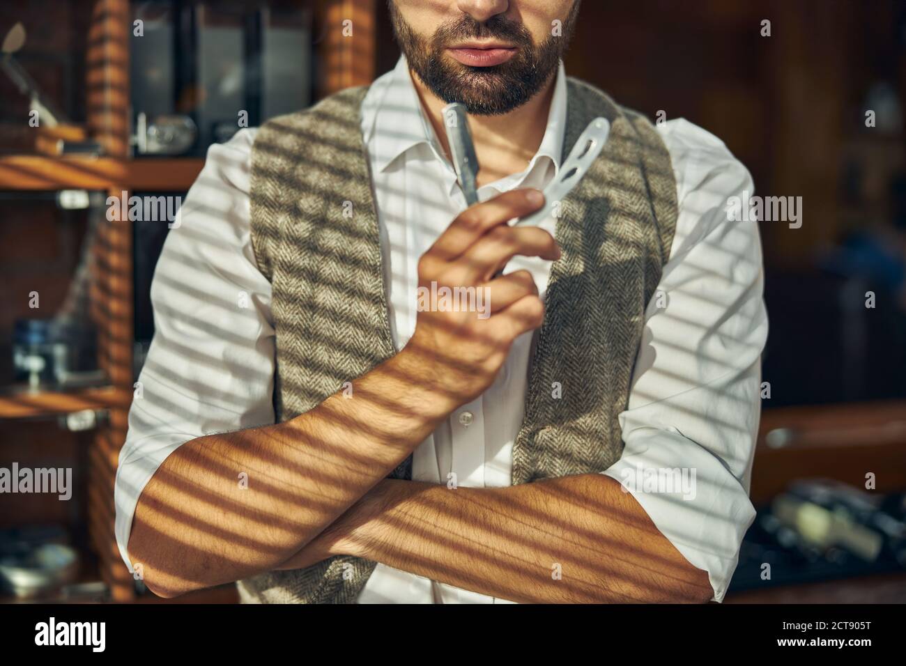 Skilled hairstylist posing with a straight razor at a Stock