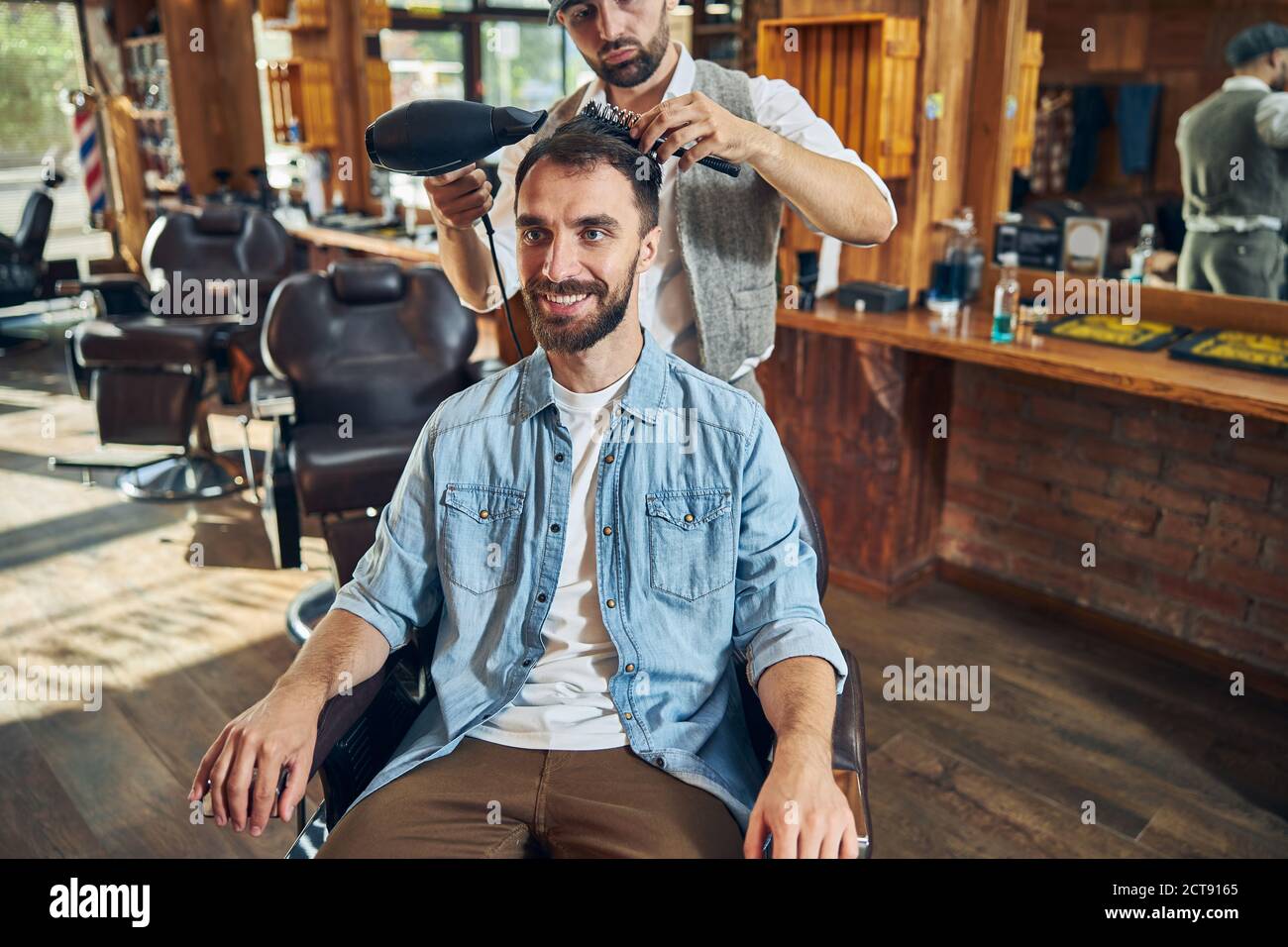 Cheerful client of a barbershop having his hair blow-dried Stock Photo