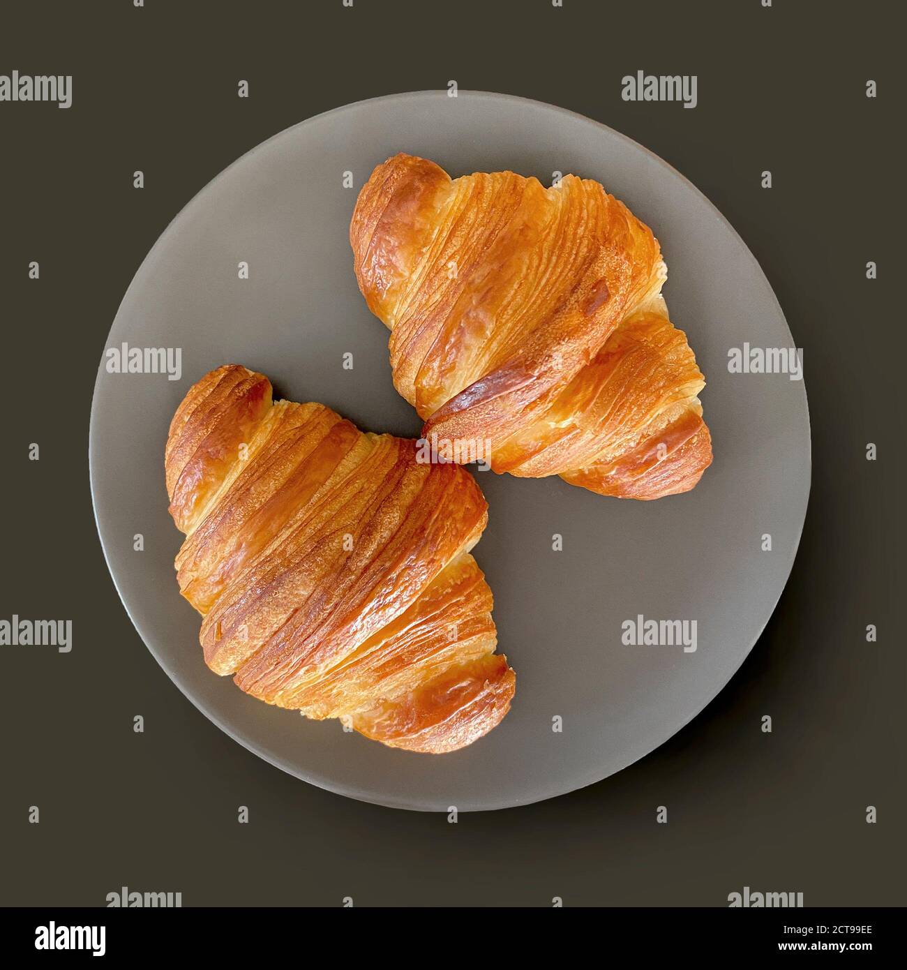 two fresh croissants on grey plate, top view Stock Photo