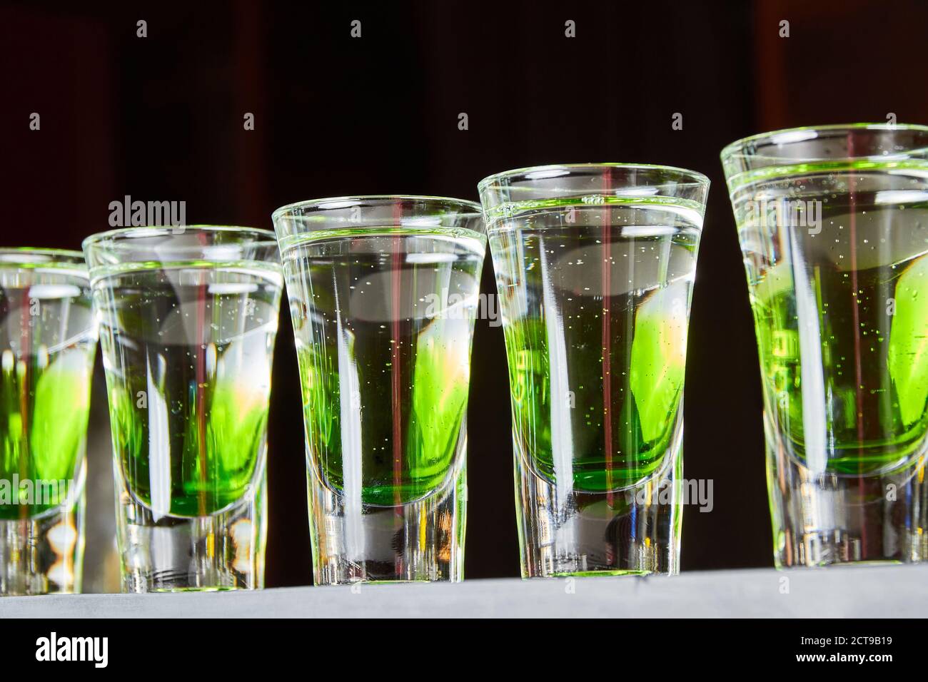 Several whitegreen alcoholic drinks shots on the bar counter Stock