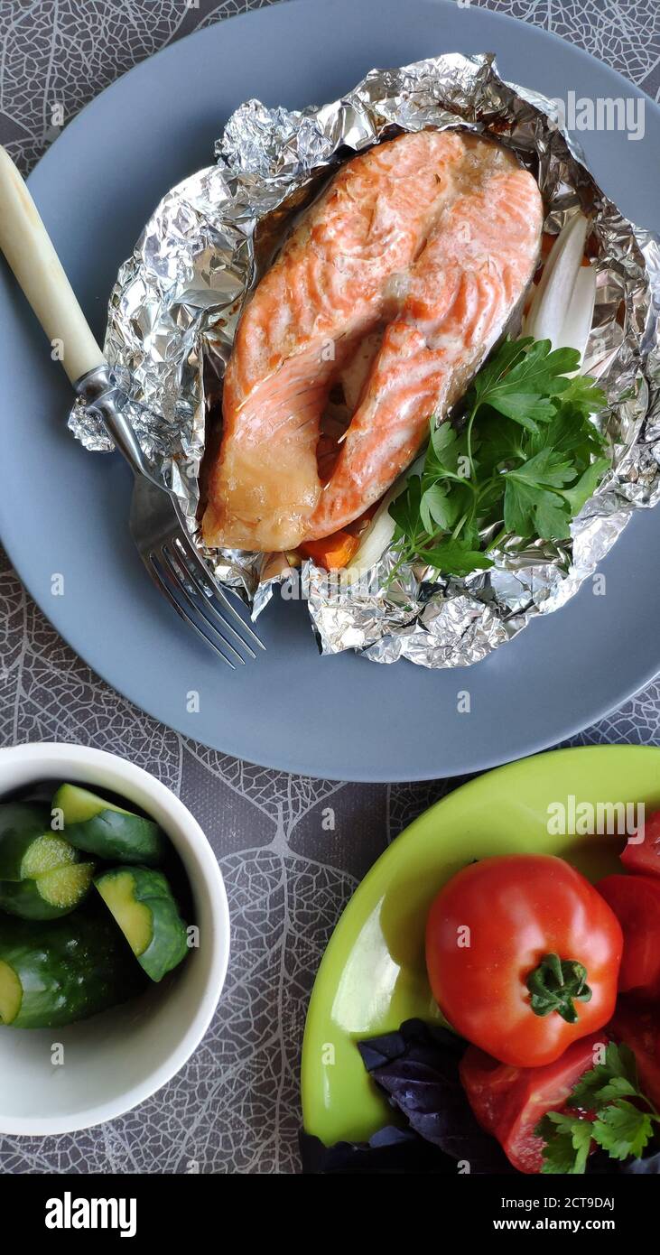 Top view of foil baked salmon steak and fresh vegetables, selective focus Stock Photo