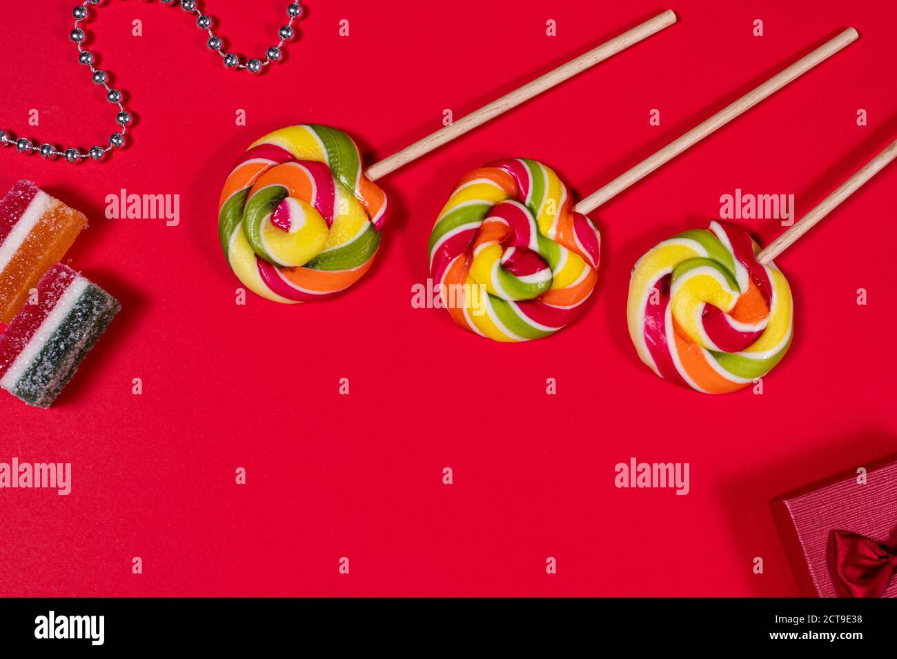 Bright candy lollipops on a stick on a red background. Sweets, sugar
